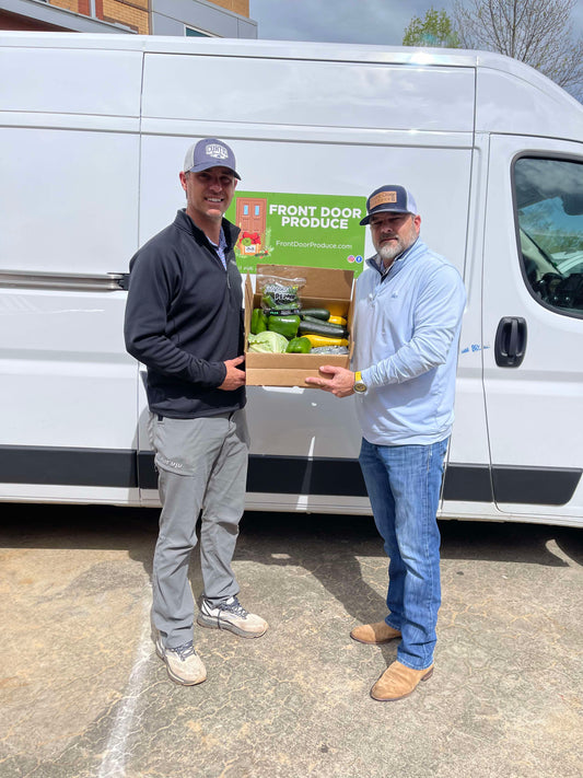 North Oconee National FFA Organization leader Tim Griffith along with Front Door Produce owner Brad Mathis, both holding a box of mixed vegetables.